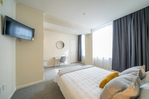 1 dormitorio con 1 cama y TV en la pared en Studio 5E, en Wellington