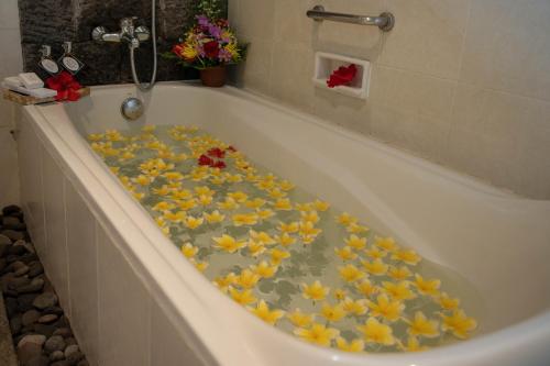 a bath tub filled with lots of yellow flowers at Bliss Ubud Spa Resort in Ubud