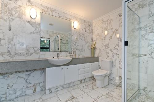 a white bathroom with a sink and a toilet at Mermaids Reach on Hamilton Island by HIHA in Hamilton Island