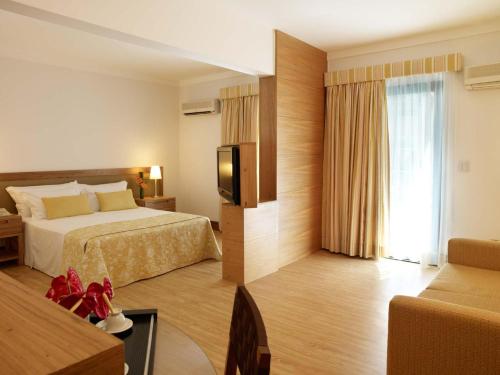 a hotel room with a bed and a television at Hotel Nacional Inn Cambuí Campinas Residence in Campinas