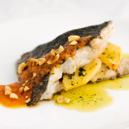 a piece of fish on a white plate with sauce at Hotel Arco de Mazarelos in Santiago de Compostela