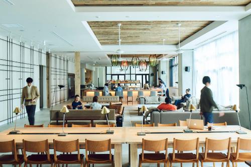 a lobby with people sitting on chairs and tables at Hotel It Osaka Shinmachi in Osaka
