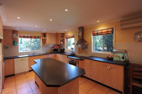 uma grande cozinha com armários de madeira e um balcão preto em Middle Ridge, Toowoomba, em Toowoomba