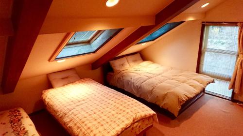 a bedroom with two beds and two windows at Guest House 合歓木（ねむ） in Hokuto