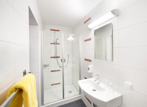 a white bathroom with a shower and a sink at Erkheimer Landhaus in Erkheim