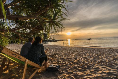 a man and a woman sitting on a bench on a beach at Lazy Days Bungalows in Ko Lanta