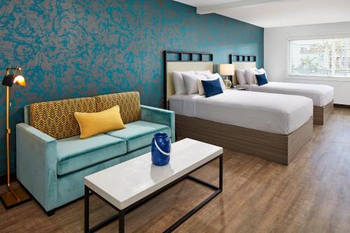 a hotel room with two beds and a couch at The Shoal Hotel La Jolla Beach in San Diego