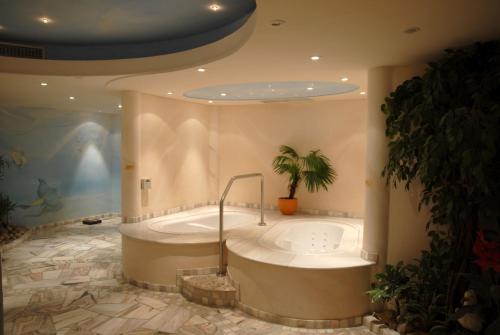 a large bathroom with a tub with a palm tree at Hotel Gasthof Wasserschloß in Mitwitz