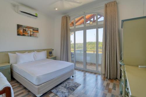 a bedroom with a bed and a large window at Shamaz Galle in Galle