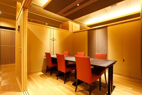 a dining room with a table and orange chairs at Kasuitei Ooya in Fujikawaguchiko