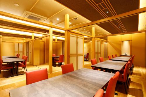 a conference room with wooden tables and red chairs at Kasuitei Ooya in Fujikawaguchiko