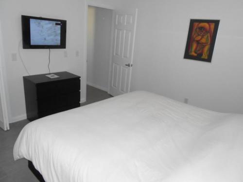 a bedroom with a white bed and a flat screen tv at Foxrun Retreat - 3BR Inverness Poolhome in Inverness