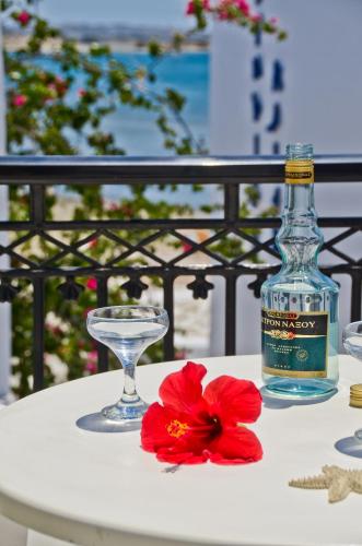 a bottle of alcohol and a red flower on a table at Soula Naxos in Naxos Chora