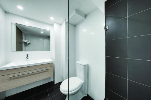 a bathroom with a toilet and a sink and a mirror at Central Studio Hotel Sydney in Sydney