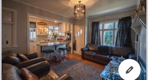 a living room with leather couches and a kitchen at Skyline SkyRides Premium Property, see host info for pets in Rotorua