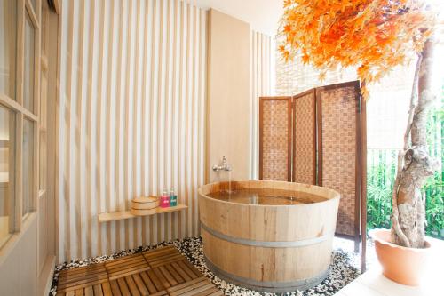 a bathroom with a wooden tub with a tree in it at Baan Kashiwaya in Bangkok