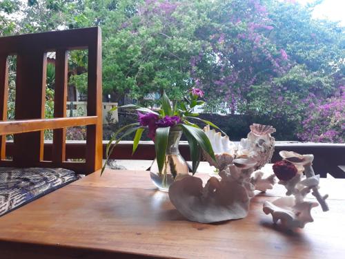 a wooden table with a vase and flowers on it at Bara Beach Bungalows in Bira