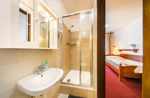 a bathroom with a sink and a shower and a bed at Pension BLUME in Český Krumlov