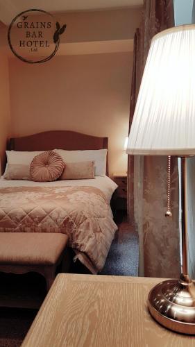 a bedroom with a bed and a table with a lamp at Grains Bar Hotel in Oldham