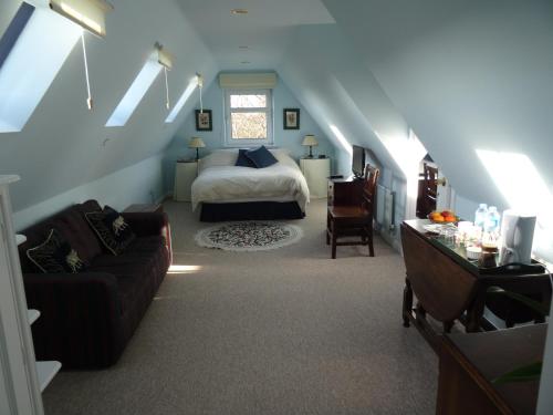 a bedroom with a bed and a couch in a room at The Newnham White House in Baldock