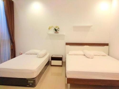 two beds in a room with white walls at Fams Homestay by FH Stay in Yogyakarta