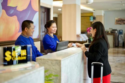 two women and a man standing at a counter at Dreamtel Jakarta in Jakarta