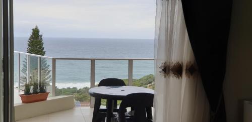 a table and chairs in a balcony with a view of the ocean at The Homestead Margate - South Africa in Margate