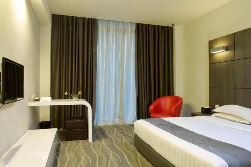 a hotel room with a bed and a red chair at Dreamtel Jakarta in Jakarta