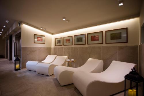a room with two white chairs and paintings on the wall at Hostellerie Du Cheval Blanc in Aosta