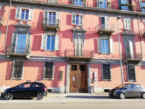 two cars parked in front of a pink building at Le Corti 2 in Alessandria