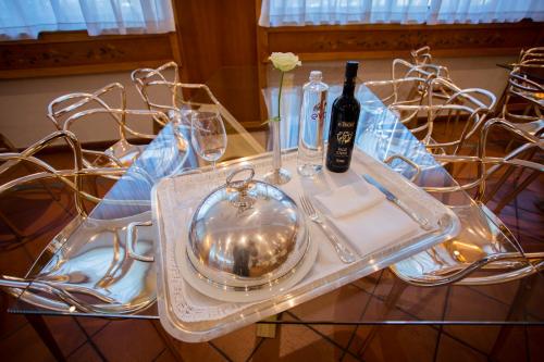 a table with a glass plate and a bottle of wine at Hostellerie Du Cheval Blanc in Aosta