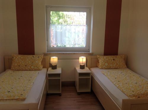 Dos camas en una habitación con dos lámparas. en Ferienwohnungen Bella Vita en Harthausen