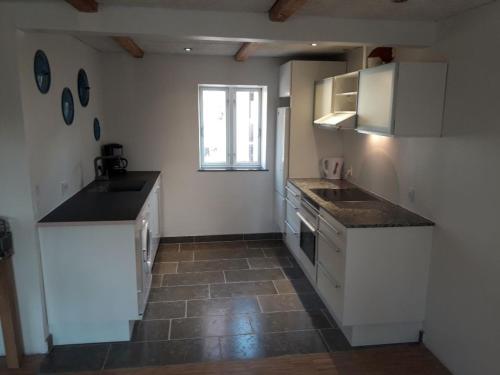 a kitchen with white cabinets and a tile floor at Elmealle 6 in Skjern