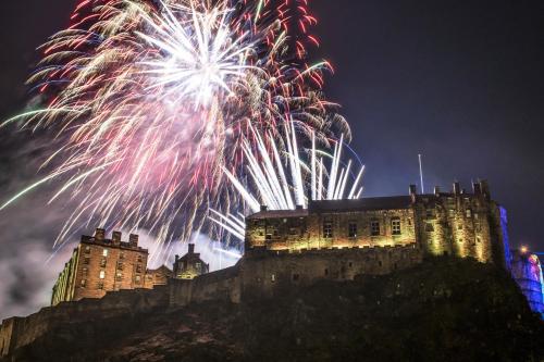 a fireworks display behind a castle at night at Grassmarket Old Town Boutique Apartment in Edinburgh