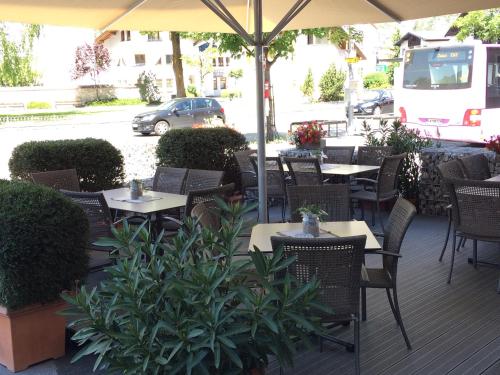 an outdoor patio with tables and chairs and an umbrella at Pension Garni Gemse in Zams