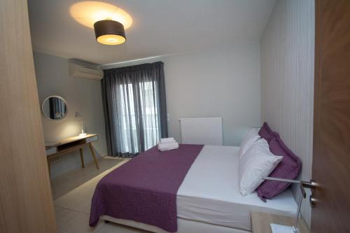 a bedroom with a bed with a purple blanket and a window at Spacious Fully Equipped 3BD 2Bath Apt in the heart of city with Balconies AC and fast WIFI #2 in Heraklio Town