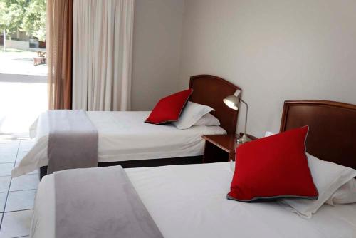 a hotel room with two beds with red pillows at The Village Guesthouse in Ceres