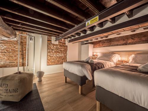 two beds in a room with brick walls at My Luxury Suites - Standard in Savona