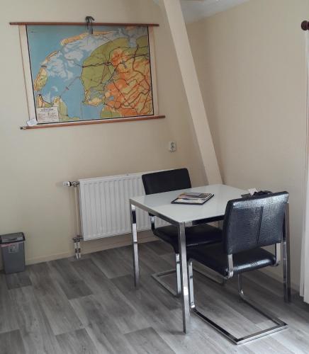 a table and chairs in a room with a map on the wall at Logement 'De witte klok' in Oude Bildtzijl