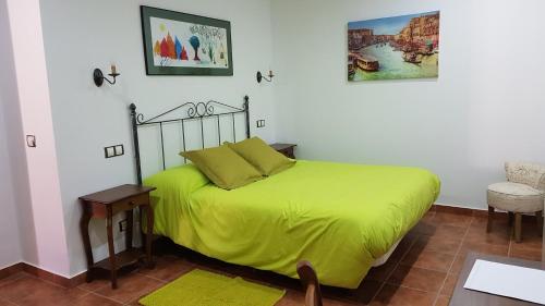 a bedroom with a bed with a green blanket at La Aldea Colorada in Mota del Marqués