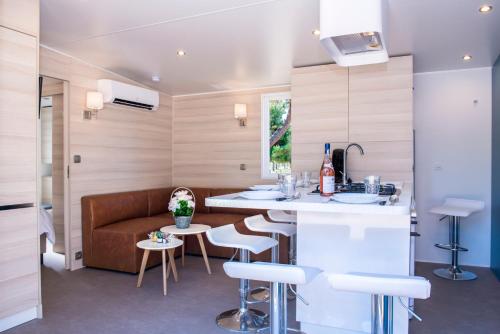 Una cocina y una sala de estar con un sofá y una mesa. en Domaine Les Mûriers, en Vendres-Plage