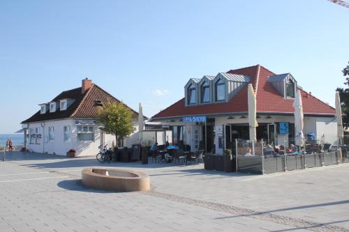 a street with buildings and a plaza with tables and chairs at Sonnengarten 10 - Ruhepol in Kellenhusen