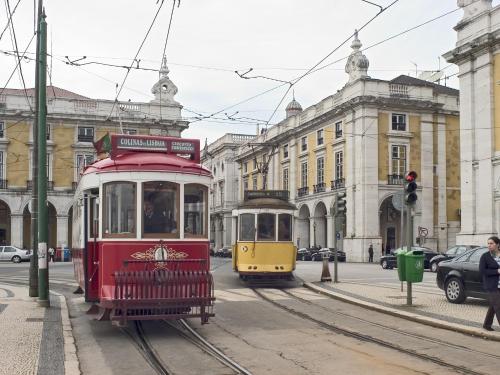 a red and yellow trolley car on a city street at Hotel ibis Lisboa Liberdade in Lisbon