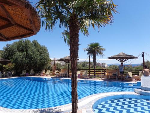 a beach with a pool, chairs, and a pool table at Angela Hotel in Agia Marina Aegina
