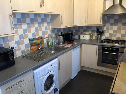 uma cozinha com um lavatório e uma máquina de lavar roupa em NEW Super 2BD Flat near Dalkeith Town Centre em Dalkeith