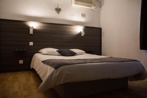 - une chambre avec un grand lit et une tête de lit en bois dans l'établissement Hôtel Althea - Piscine et Sauna, à Béziers