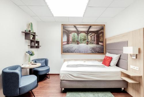 a bedroom with a bed and two blue chairs at Pallas Hotel in Darmstadt