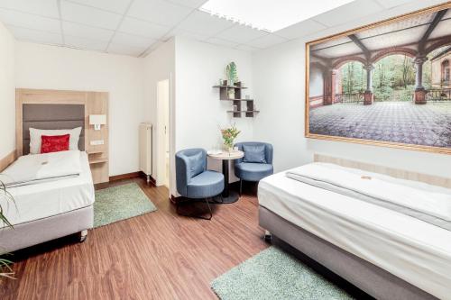 a bedroom with two beds and a table and two chairs at Pallas Hotel in Darmstadt