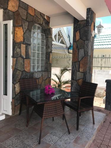 a table and chairs on a patio with a stone wall at Oceanpride Complex in Flic-en-Flac