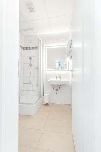 a white bathroom with a shower and a sink at Pallas Hotel in Darmstadt